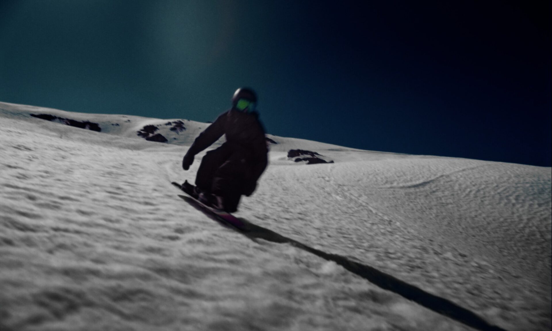 Snowboarder descending a sunlit slope