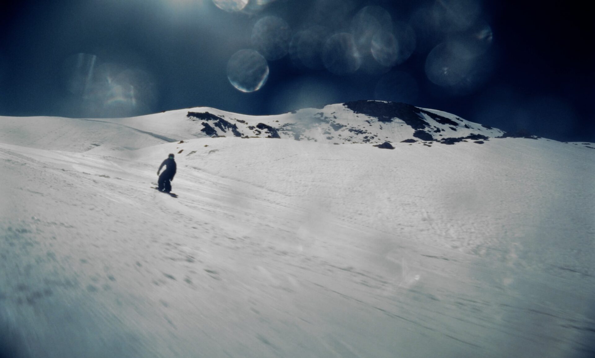 Snowboarder in an open mountain landscape