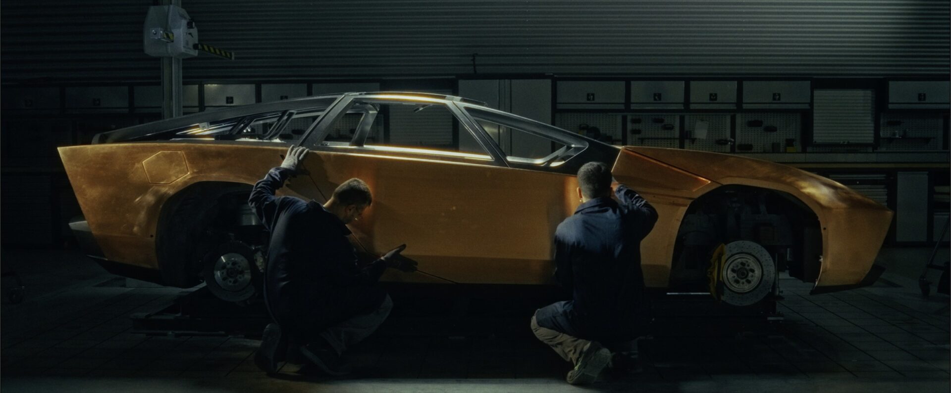 People beside a yellow car in a workshop